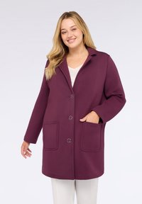 Cappotto in misto lana color bordeaux con colletto, tre bottoni e due tasche frontali, caratterizzato da una vestibilità rilassata e una texture liscia.