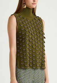 Haut sans manches vert olive à col montant, avec un tricot texturé agrémenté d'accents violets, associé à un pantalon à motifs dans des tons assortis.