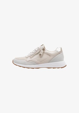 Zapatilla deportiva beige clara con paneles laterales perforados, cordones delanteros, cremallera lateral y suela blanca con dibujo marrón.