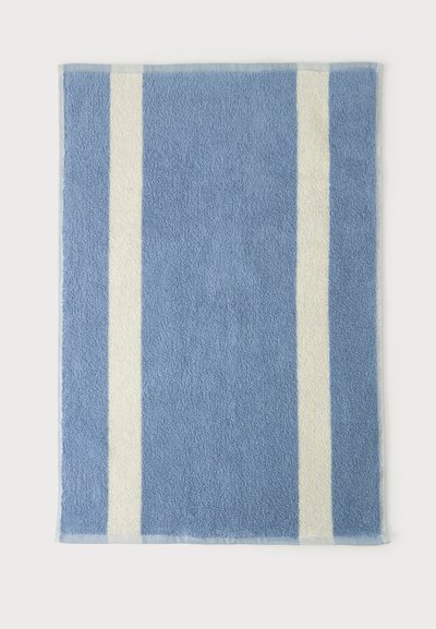 Tapis de bain rectangulaire bleu avec deux bandes blanches verticales près de chaque côté sur un fond clair uni.
