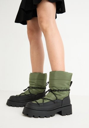 Rohkead rohelised pehmendusega pahkluu saapad mustade kummitaldade ja paeltega. Ülemine osa on tikandiga tekstuuriga. Tugev ja jäme tallakonstruktsioon, mis tagab parema haarde ja stabiilsuse.