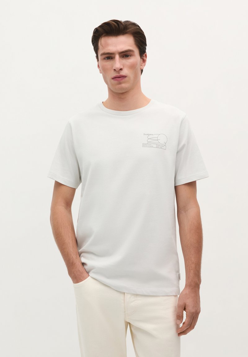 Lys grå t-shirt lavet af bomuld, med et simpelt linjeteckning design på venstre brystområde. Korte ærmer og rund halsudskæring.