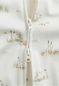 Combinaison zippée en tissu blanc avec un motif de canards et de canetons, dotée d'une fermeture éclair lisse et d'une texture douce.