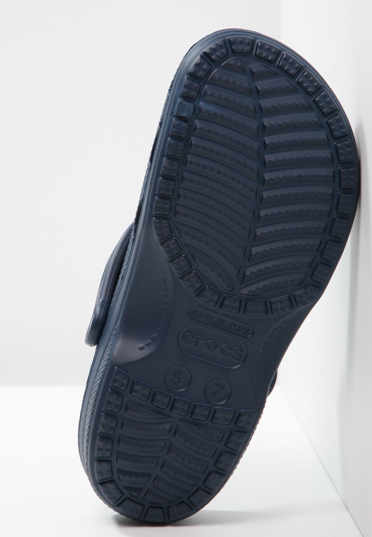 Suola di Crocs blu navy con gomma testurizzata, scanalature profonde per la trazione e logo in rilievo con indicazioni della misura.