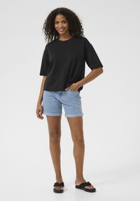 Black short-sleeve top with a round neck and straight silhouette, paired with light blue denim shorts and black sandals.
