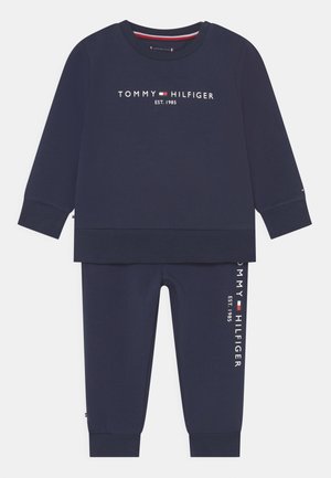 Granatowy zestaw składający się z bawełnianej bluzy i spodni dresowych z napisem i logo "TOMMY HILFIGER". Miękka faktura, ściągacze przy mankietach i dolnych krawędziach.