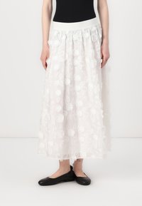 Witte maxi rok met bloemenborduurwerk en getextureerde pompons, met een elastische tailleband en een vloeiende silhouet. Draag het met zwarte flats.