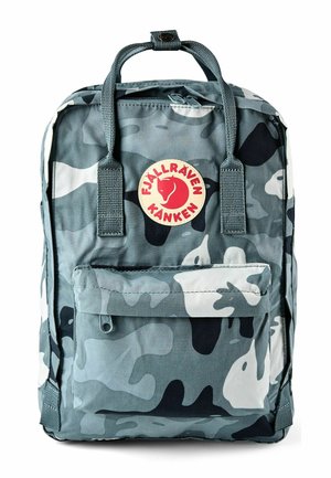 Mochila Fjällräven Kånken en camuflaje gris y blanco, con asas superiores, bolsillo frontal con cremallera y parche circular con logo rojo.