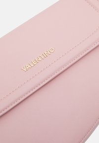 Rosa fusk läder plånbok med guld "Valentino"-logotyp, med en slät yta och ren design, accentuerad av noggrant stygn längs kanterna.