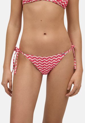 Bikini inferior en patrón de zigzag rosa y blanco, diseño de tiro bajo con lazos laterales, confeccionado con tela suave y elástica para mayor comodidad.