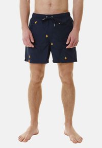 Pantaloni da bagno blu navy con vita regolabile, decorati con piccoli motivi di ananas e anatra. Materiale leggero, lunghezza a metà coscia e texture liscia.