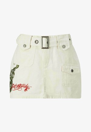 Bílá bavlněná sukně s páskem v pase, postranními kapsami a složitými zelenými a červenými výšivkami. Texturovaná látka se strukturovaným tvarem.