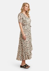 Langes, fließendes Kleid mit einem pinken und beigen Zickzackmuster. Verfügt über ein Wickeldesign, kurze Ärmel und einen Bindegürtel in der Taille. Weicher Stoff.
