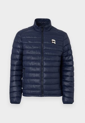 Mørkeblå dunjakke med høy krage, quiltet design, sidelommer og en liten logo på brystet. Glatt tekstur.