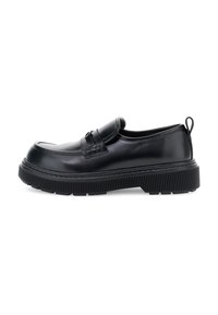 Mocasín de cuero negro con suela gruesa y estriada, detalle de cinta y asa en el talón, mostrado en perfil izquierdo sobre fondo blanco.