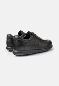Par de zapatillas casuales de cuero negro con cordones beige, suelas redondeadas y detalle de costura en los laterales sobre un fondo blanco.