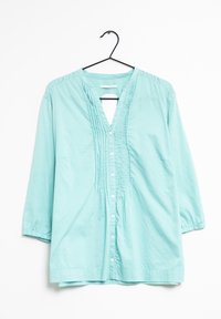 Camicia in cotone azzurro chiaro con scollatura a V, dettagli plissettati sulla parte anteriore e maniche a tre quarti. Cinque bottoni lungo la chiusura anteriore.