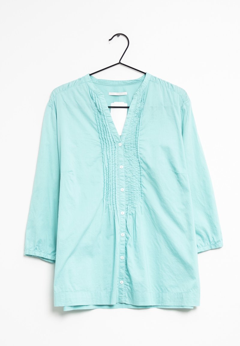 Camicia in cotone azzurro chiaro con scollatura a V, dettagli plissettati sulla parte anteriore e maniche a tre quarti. Cinque bottoni lungo la chiusura anteriore.