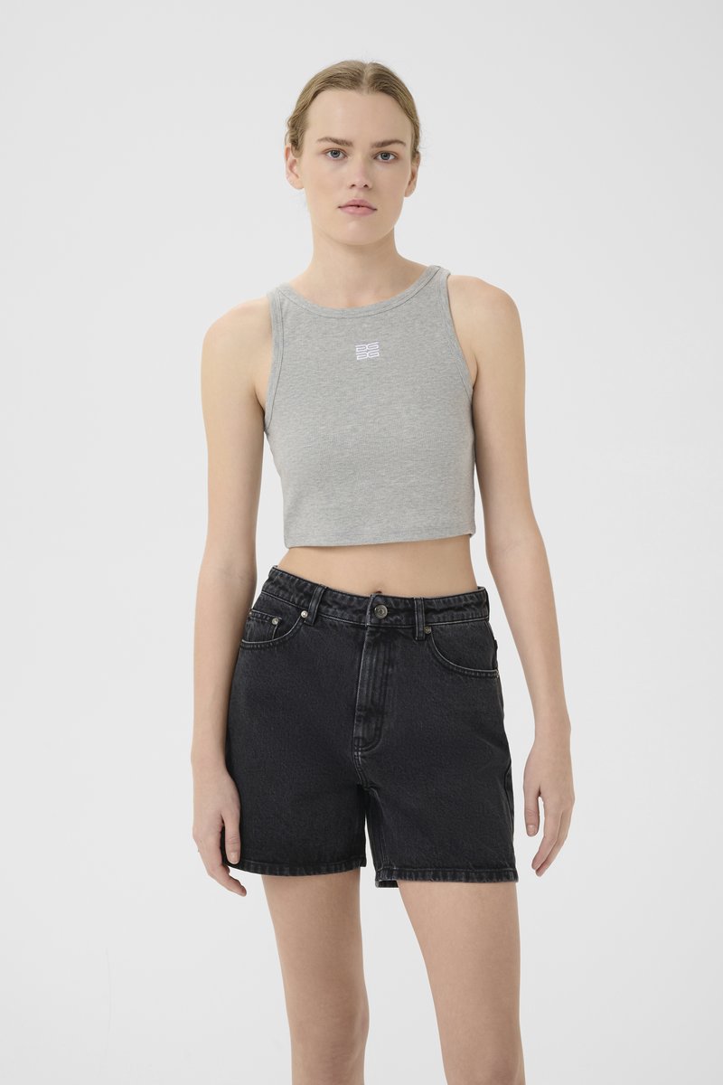 Grått kort tanktop med logo på brystet, kombinert med høytlivede svarte denimshorts med frontlommer og teksturert overflate.