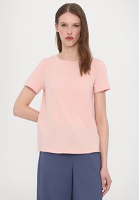 Lys rosa kortermet t-skjorte med rund hals og myk stoff. Designet har en avslappet passform, minimale sømmer og ingen synlige mønstre.