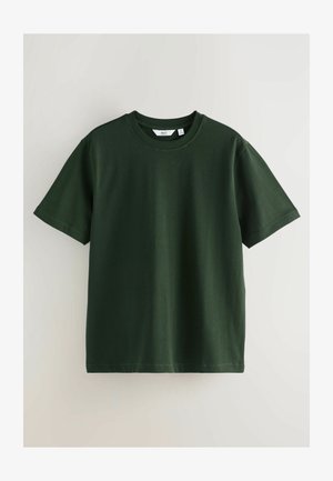 T-shirt à manches courtes vert foncé en coton lisse. Il présente un col rond et une coupe décontractée. Des détails de couture sont visibles le long des manches.