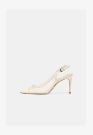 Roomkleurige high-heeled slingback schoen met puntige neus, kleine strikdetail en verstelbare gesp aan de enkel op een effen achtergrond.