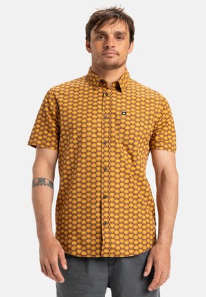 Short-sleeve button-up shirt in orange and yellow checkered pattern. Made of lightweight fabric, featuring a chest pocket and black logo detail.