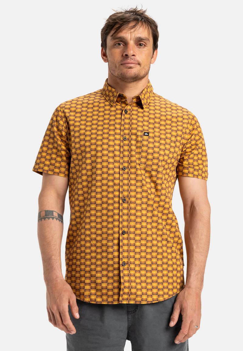 Short-sleeve button-up shirt in orange and yellow checkered pattern. Made of lightweight fabric, featuring a chest pocket and black logo detail.