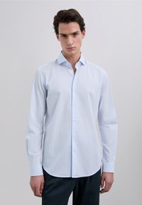 Camisa azul claro de botones con mangas largas, cuello puntiagudo y dobladillo recto. La tela parece suave, con una textura sutil.