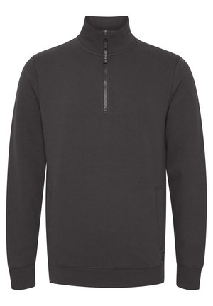 Tumši pelēks džemperis ar augstu apkakli, ar pusi rāvējslēdzēja priekšpusi, garām piedurknēm un priekšējām kabatām. Gluda tekstūra un minimālistisks dizains.