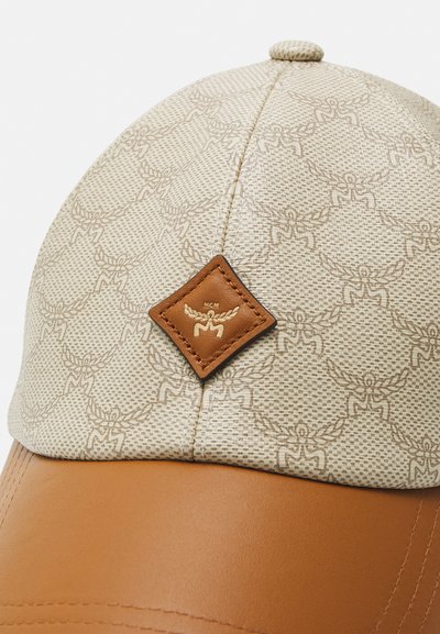 Casquette en tissu beige à motifs, avec une visière en cuir lisse marron et un patch en cuir gaufré brodé sur le devant.