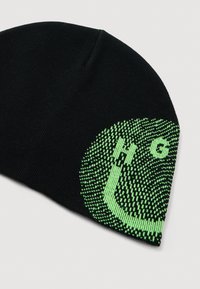Czarna dzianinowa czapka beanie z zielonym pikselowym wzorem oraz literami "H" i "G" blisko krawędzi na jednolitym jasnym tle.