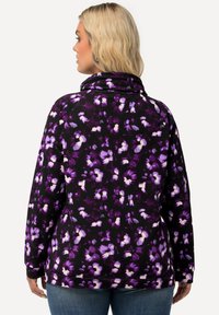 Maglione floreale nero con motivi di fiori viola e bianchi, caratterizzato da un colletto alto e maniche lunghe. Tessuto morbido con una vestibilità comoda.