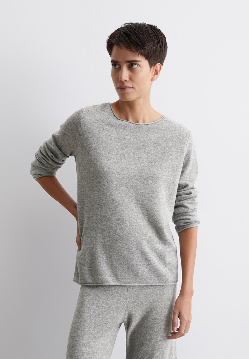 Szary sweter z długim rękawem, wykonany z miękkiego dzianiny, z okrągłym dekoltem i podwiniętymi rękawami, w zestawie ze spodniami w tym samym odcieniu. Gładka tekstura.