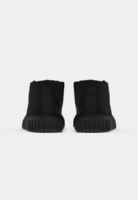 Sneakers nere alla caviglia con parte superiore testurizzata, tallone rinforzato e suola in gomma rigata. Presentano pannelli elastici laterali per una vestibilità ottimale.