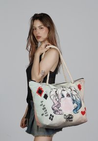 Bolsa tote con un diseño impreso de un personaje con chicle, hecha de lona, con una combinación de colores en dos tonos y asas de cuerda.