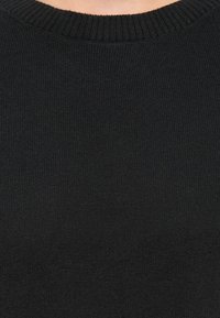 Black knitted crew neck sweater shown from chest to neck.