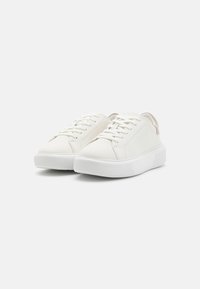 Weiße Sneakers aus glattem Leder mit Schnürdesign, runder Zehenpartie und einer gerippten weißen Gummisohle. Mit einem beigen Fersen-Patch akzentuiert.