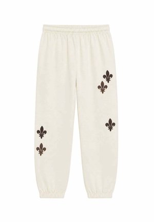 Pantalones deportivos de color crema con cintura elástica y puños, decorados con seis símbolos oscuros de flor de lis en ambas piernas.