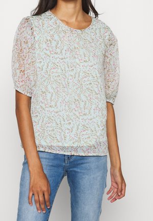 Jasnoniebieska bluzka w kwiatowy wzór z różowymi kwiatami i brązowymi łodygami. Krótkie bufiaste rękawy i zaokrąglony dekolt. Lekki materiał.