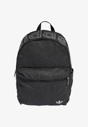 Mustast tekstiiidest seljakott ümarate vormidega, millel on suur logo esiküljel, lukuga taskud ja väike logomärgis põhjas.