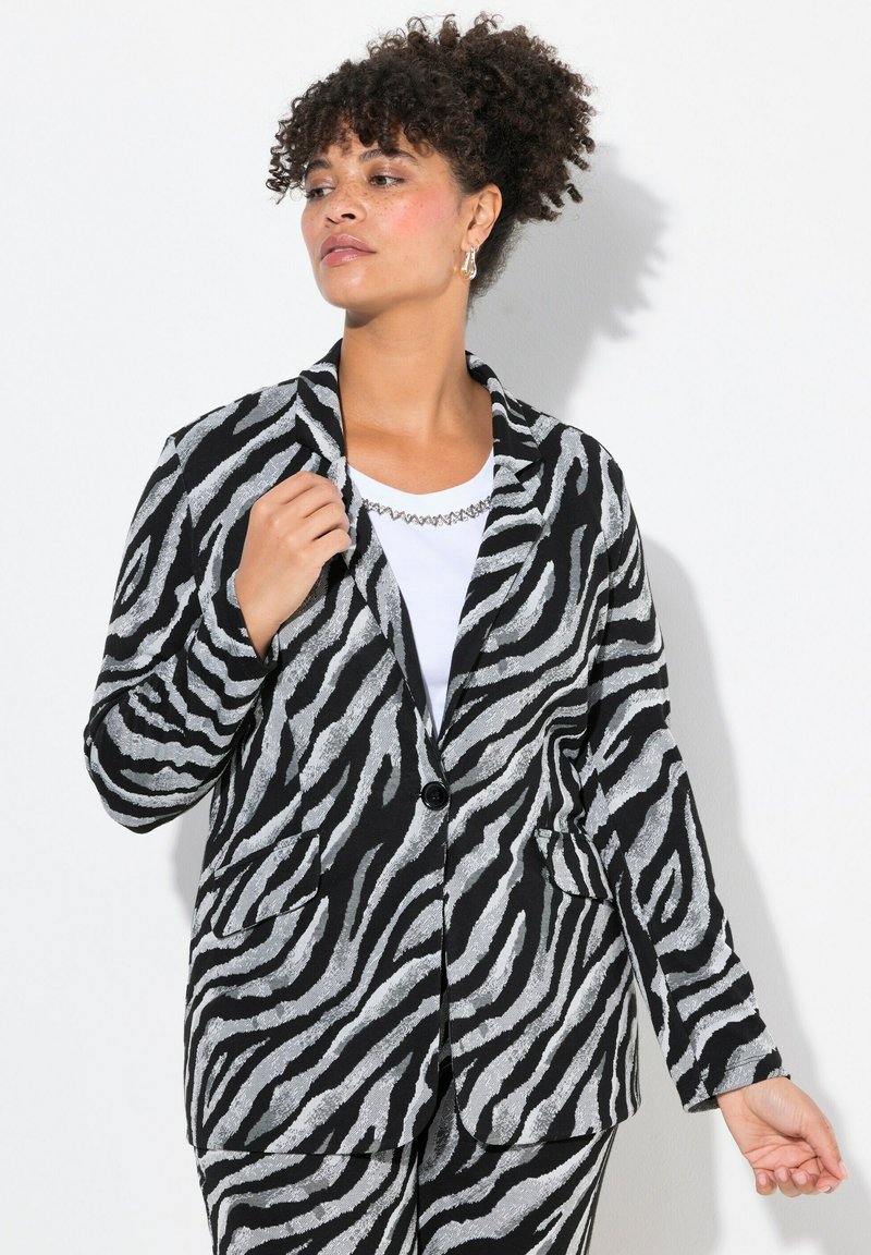Zwart-witte blazer met zebraprint en een gestructureerde afwerking, voorzien van lange mouwen, een enkele knoopsluiting en twee voorzakken.