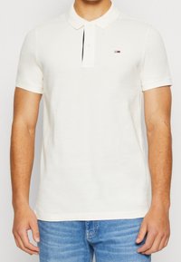 Camisa polo blanca de manga corta, con cuello de botones y un pequeño logo en el lado izquierdo del pecho. Fabricada en suave tela de algodón.