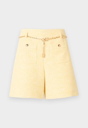 Shorts taille haute texturés jaunes avec poches avant et ceinture fine en chaîne dorée ornée de détails en forme de breloques circulaires.
