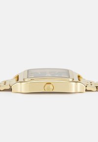 Goldfarbener rechteckiger Uhr mit einem strukturierten schwarzen Zifferblatt, sechseckiger Krone und einer verbundenen Metallarmband, von der Seite gezeigt.