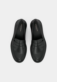 Black leather loafers with a smooth finish, featuring dual stitched detailing and a tapered toe design. Logo visible on the insole.