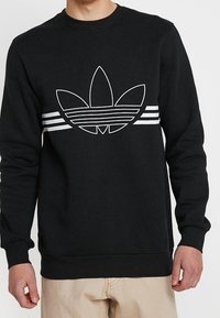 Svart sweatshirt i bomull med rund halsringning, prydd med en vit tre-stripes design och en stor vit logotyp framtill.