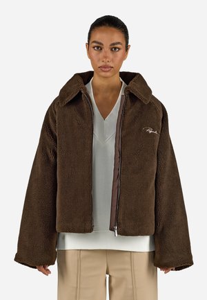 Brown fleece jacket with a boxy design, large collar, and zip front. Features contrasting inner lining and embroidered logo detail.