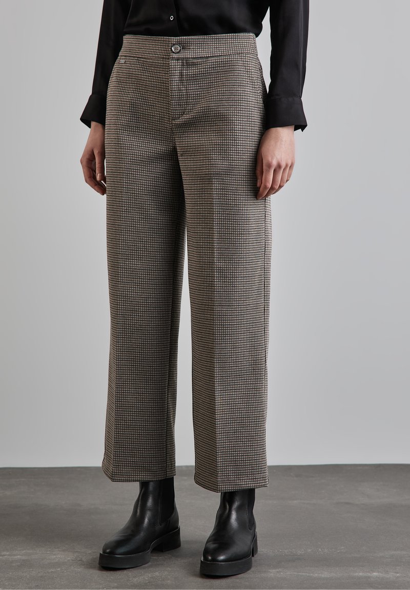 Brown checkered trousers made of woven fabric feature a straight fit, mid-rise waist, and a button closure. Paired with black ankle boots.
