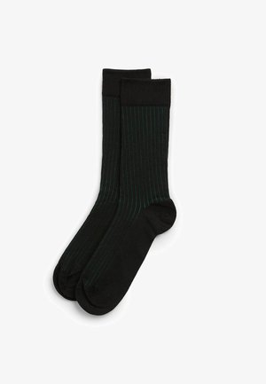 Czarne skarpetki z zielonymi pionowymi paskami, charakteryzujące się gładką teksturą i prążkowanym mankietem. Standardowa długość do kostki zapewniająca komfortowe dopasowanie.